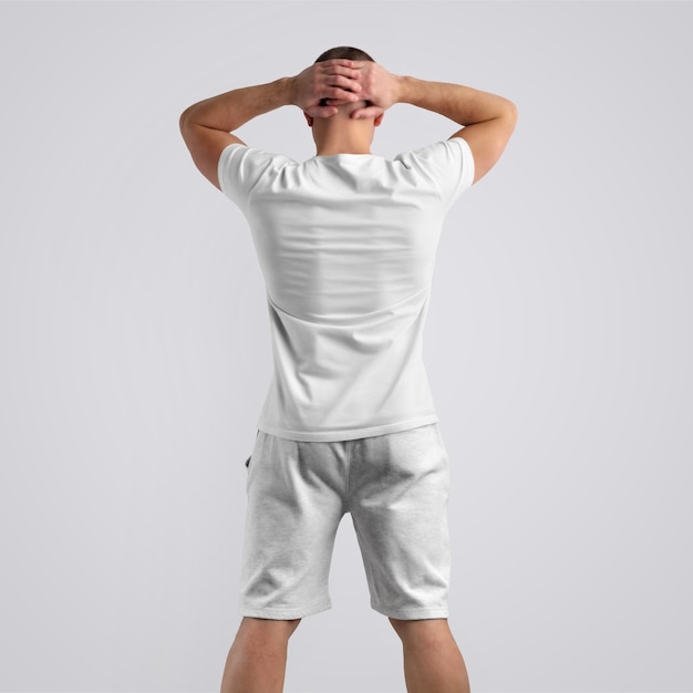 Homem magro elegante em uma camiseta em branco e shorts cinza de malha em um fundo branco do estúdio. pose de costas. o modelo pode ser usado em seu design.