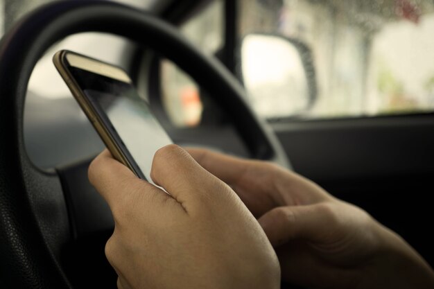 homem mão texting celular dentro de um carro