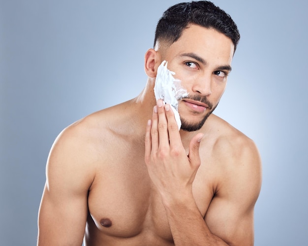 Homem mãos e aplicar espuma de barbear para depilação com higiene da pele e transformação do rosto em estúdio Pessoa masculina dermatologia e creme ou produto de sabão para manutenção da barba por fundo cinza