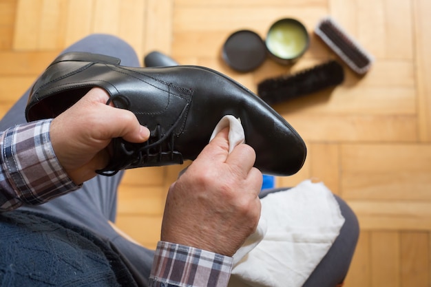 Homem mãos limpando seus sapatos com um pano e cera de sapato para melhor condição de seus sapatos, engraxando sapatos