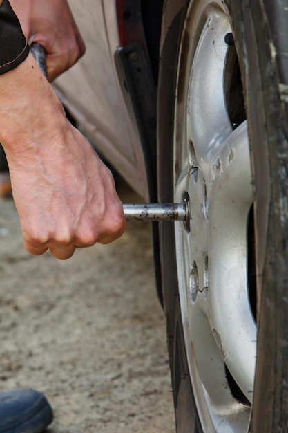 Homem mecânico de automóveis com chave de fenda elétrica trocando pneu fora do serviço de carro As mãos substituem pneus nas rodas Conceito de instalação de pneus