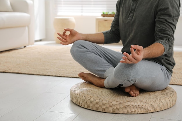 Homem meditando na esteira de vime em casa closeup