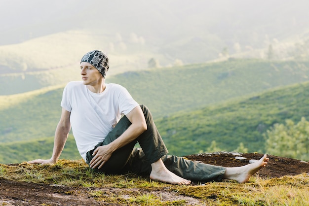 Homem meditando na montanha pela manhã. Fazendo ioga ao ar livre.