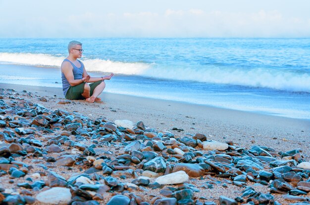 Homem meditando na praia