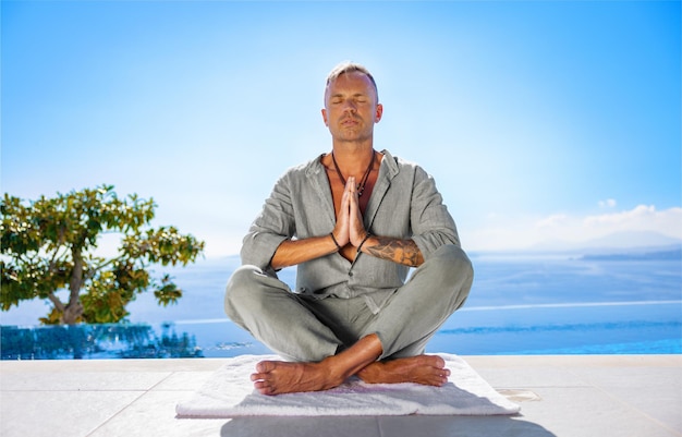 Homem meditando no terraço com bela vista para o mar