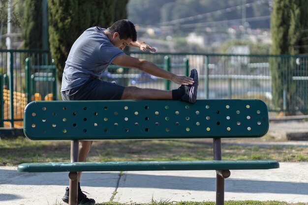 Homem mexicano se espreguiçando em um banco de parque, treinamento urbano
