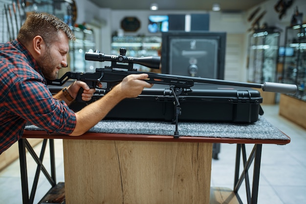 Homem mira com rifle de atirador em loja de armas