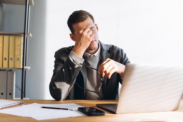 Homem moderno com óculos trabalhador de escritório cansado no trabalho