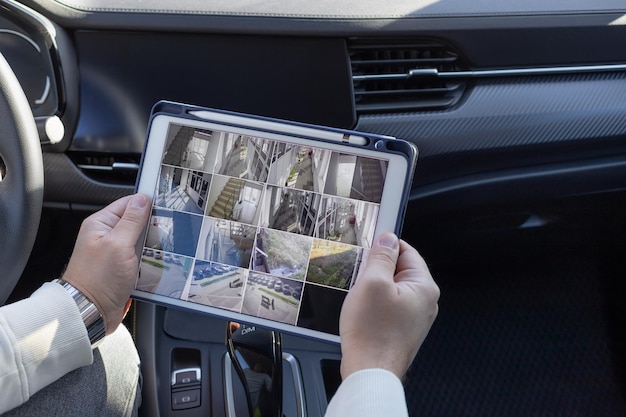 Foto homem monitorando câmeras cctv modernas em um tablet digital sentado no sistema de segurança on-line do carro