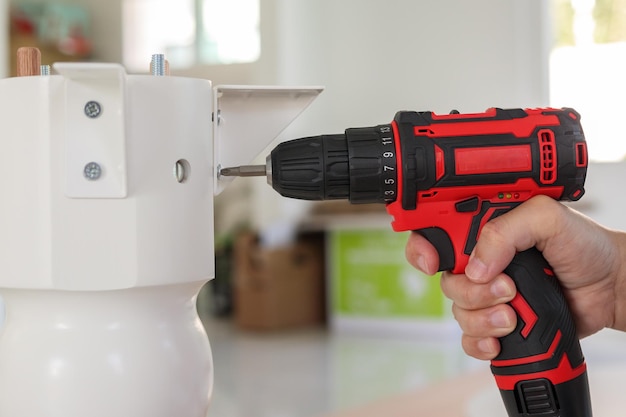 Homem montando móveis de mesa brancos em casa usando uma chave de fenda sem fio