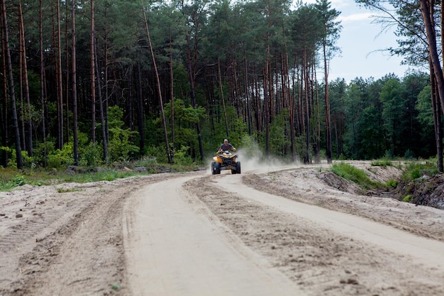 Homem montando um veículo todo-o-terreno quadriciclo amarelo em uma floresta arenosa Atração turística de aventura de esporte radical