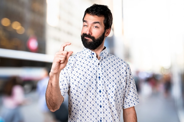 Homem moreno bonito com barba fazendo sinal minúsculo