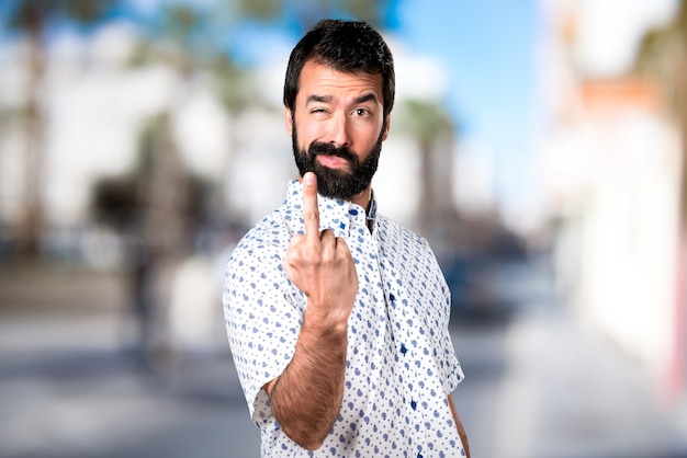 Homem moreno bonito com barba fazendo um gesto de chifre