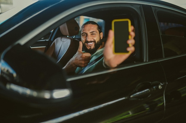 Foto homem moreno bonito jovem conectado mostrando seu smartphpone