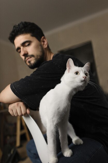 Foto homem moreno com amizade engraçada de gato branco entre homem e gato