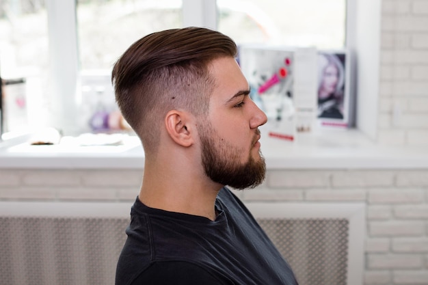 Homem moreno com corte de cabelo elegante no fundo da barbearia