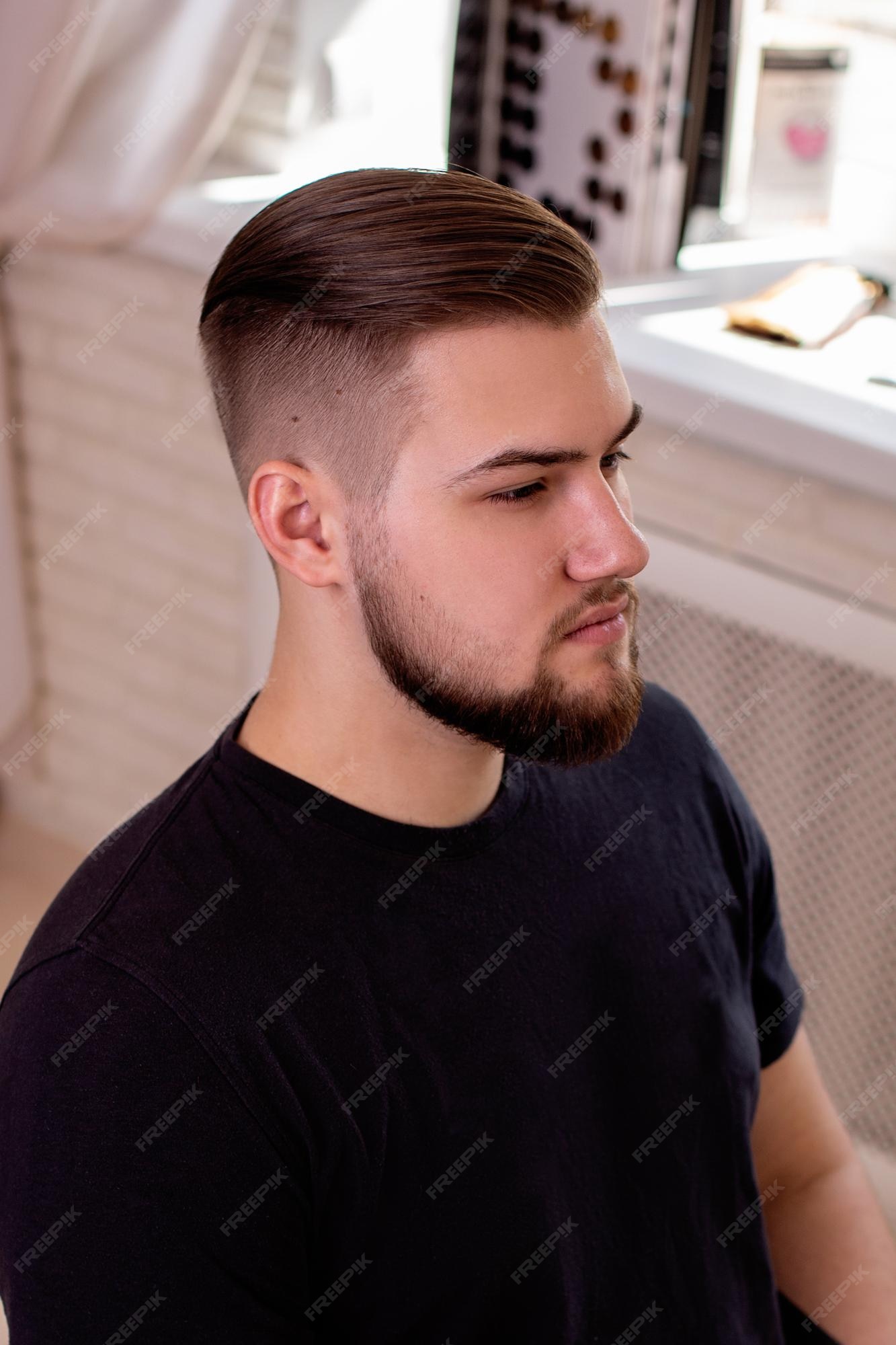 Homem moreno com corte de cabelo elegante no fundo da barbearia