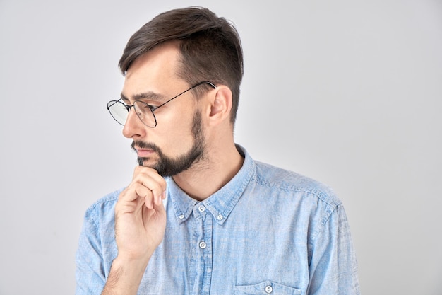 Homem moreno inteligente no queixo casual acha que as dúvidas tomam a decisão isolada no fundo azul do estúdio