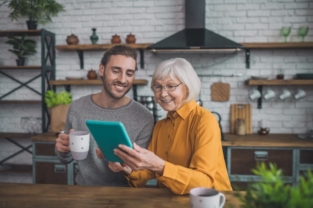 Homem mostrando à mãe como usar o tablet