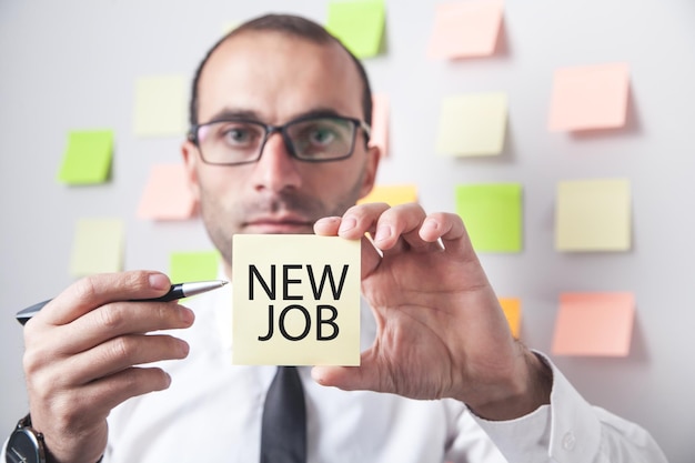 Homem mostrando mensagem de novo emprego em nota autoadesiva