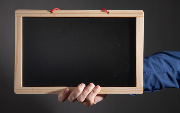 Homem mostrando o quadro-negro vazio da escola