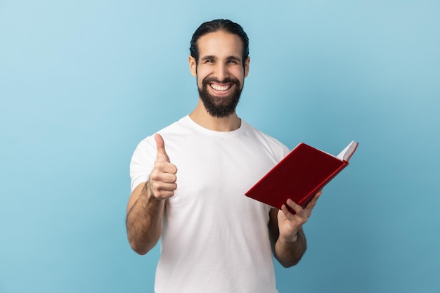 Homem mostrando os polegares para cima gesto segurando e lendo livro gosta de gênero e enredo