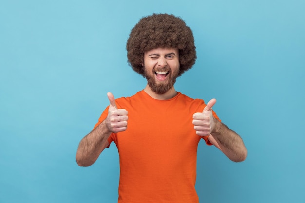 Homem mostrando os polegares para cima piscando e sorrindo animadamente desfrutando de excelente resultado