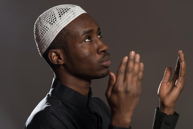 Homem muçulmano africano fazendo oração tradicional a Deus enquanto usava um boné tradicional Dishdasha