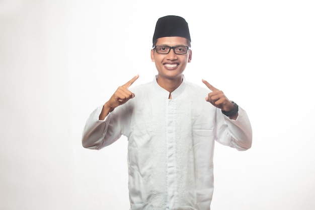 Foto homem muçulmano asiático com óculos pele castanha sorrindo de frente para a câmera e ambas as mãos apontando para a frente