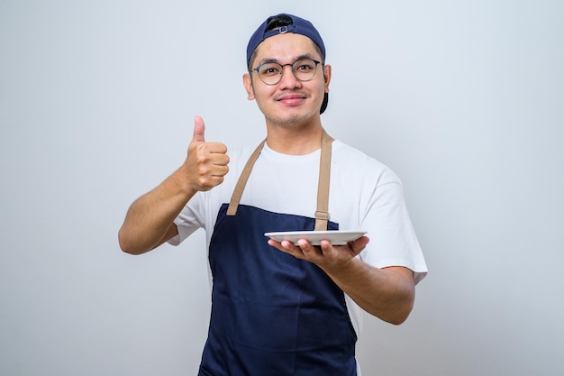 Homem muçulmano asiático mostrando expressão animada enquanto segura o prato vazio