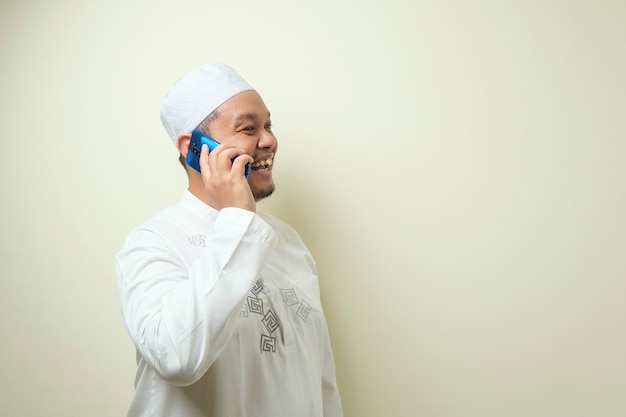 Homem muçulmano asiático parece feliz ao receber uma ligação de seu irmão. o homem comemorou eid mubarak com gesto confiante
