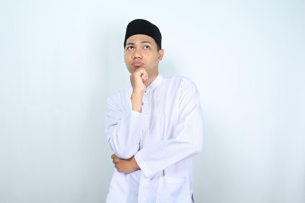 Foto homem muçulmano asiático pensativo olhando para cima pensando com a mão no queixo isolado em fundo branco