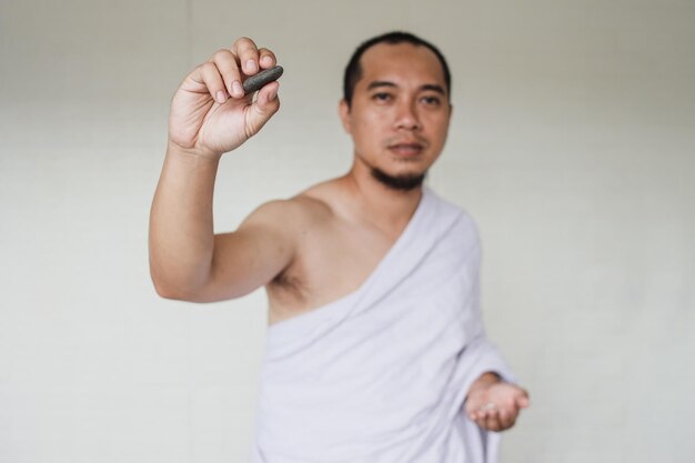 Homem muçulmano asiático realizando o ritual Jamarat (apedrejar o diabo) durante a temporada de Hajj