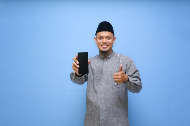 Foto homem muçulmano asiático segurando telefone e apontando o dedo para o celular pronto para pagar zakat ramadan