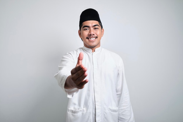 Foto homem muçulmano asiático sorrindo amigável oferecendo aperto de mão como saudação e boas-vindas