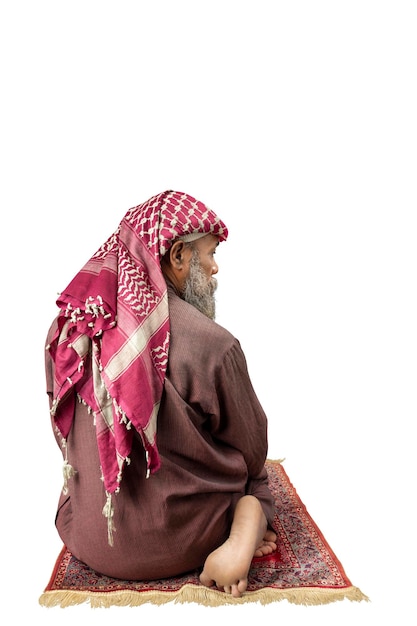 Homem muçulmano com barba usando keffiyeh com agal em posição de oração salat no tapete de oração