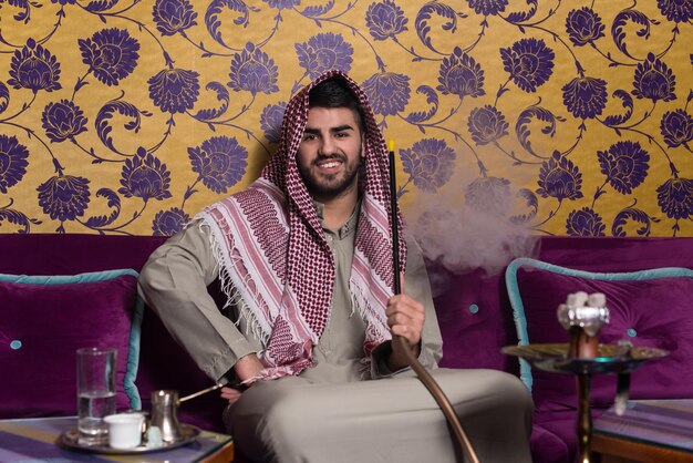 Homem muçulmano fumando o cachimbo de água tradicional