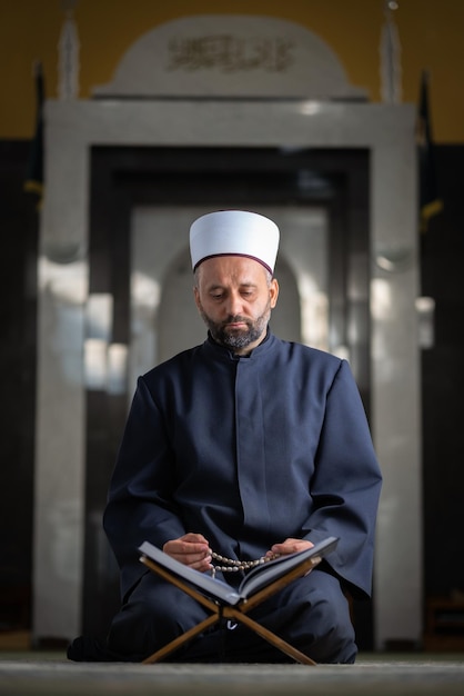 Homem muçulmano religioso lendo um Alcorão enquanto rezava dentro da mesquita.