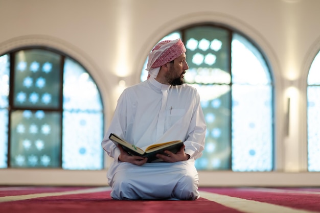 homem muçulmano rezando a Alá sozinho dentro da mesquita e lendo o livro sagrado islâmico Alcorão