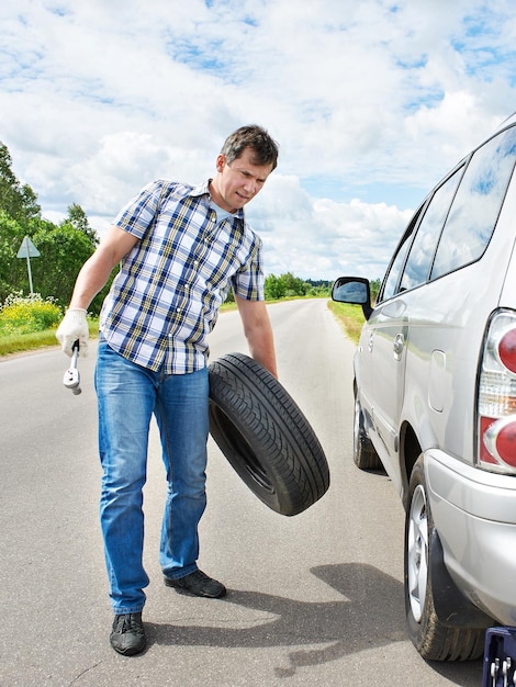 Homem mudando um pneu sobressalente de carro