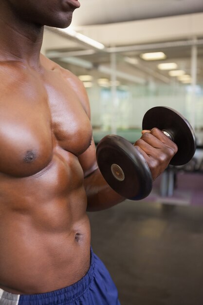 Homem muscular exercitando com dumbbell na academia