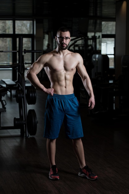 Homem muscular flexionando músculos na academia