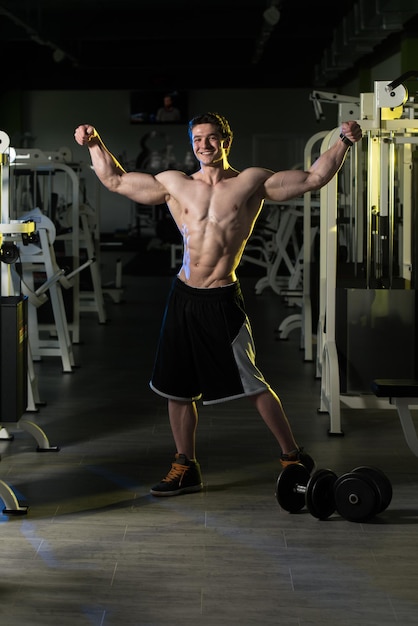 Homem muscular flexionando músculos na academia