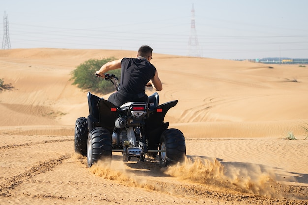 Homem musculoso andando de quadriciclo no deserto