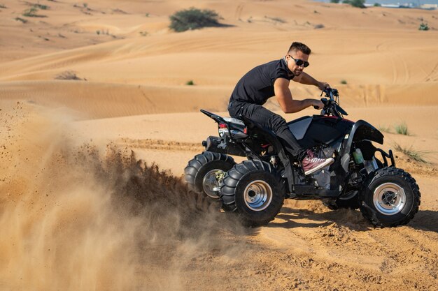 Homem musculoso andando de quadriciclo no deserto