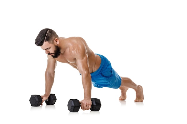 Homem musculoso atlético fazendo exercícios com halteres. Fisiculturista forte com torso nu em fundo branco