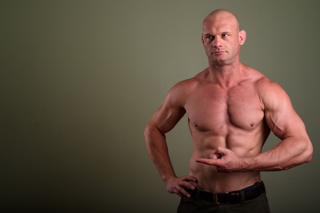 Foto homem musculoso careca sem camisa contra parede colorida