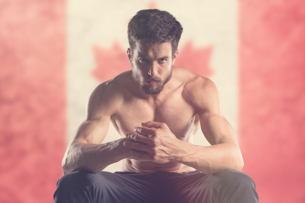 Homem musculoso com bandeira canadense atrás