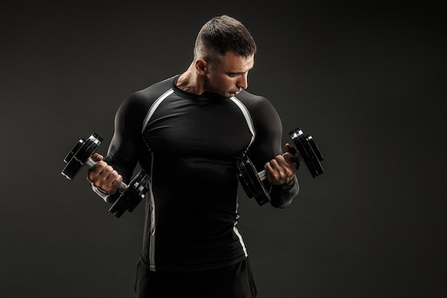 Foto homem musculoso concentrado fazendo exercício com halteres