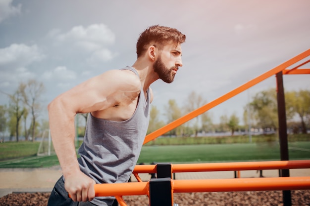 Homem musculoso e atraente está fazendo exercício na barra horizontal ouside